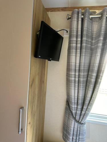 a tv hanging on a wall next to a curtain at Duckpool 108 Bude in Bude