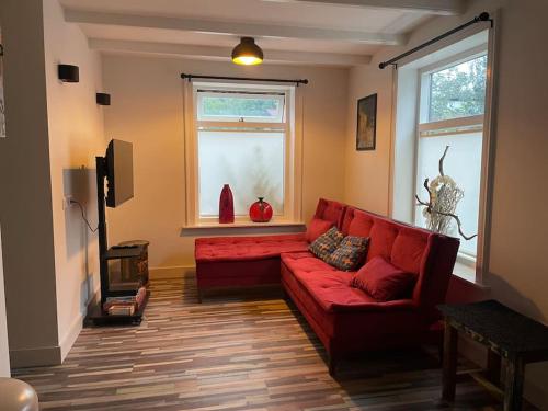 a living room with a red couch and a window at Wijk aan Zee de Wilde Roos in Wijk aan Zee