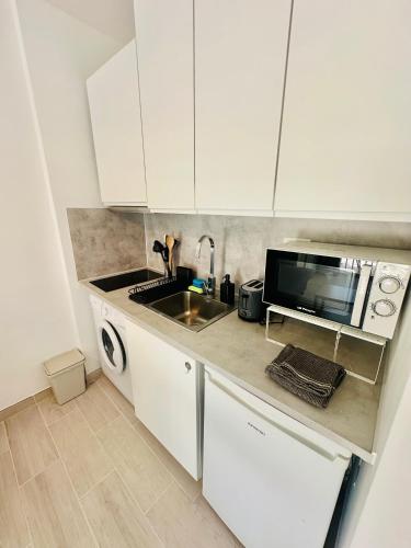 eine weiße Küche mit Spüle und Mikrowelle in der Unterkunft Apartamento Eureka Costa Del Silencio in Costa Del Silencio