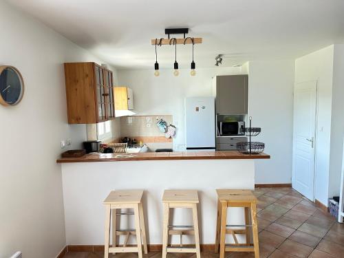 une cuisine avec trois tabourets de bar et un comptoir dans l'établissement Maison Familiale Proche Plage, Marché & Commerces - 6 pers. Classée 3 étoiles, à La Brée-les-Bains
