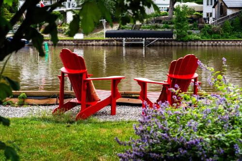 two red chairs sitting in front of a lake at Charming riverside cottage, walk to beach in Wasaga Beach