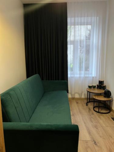 Una sala de estar con un sofá verde y una ventana. en Pretty Room Centrum, en Suwałki