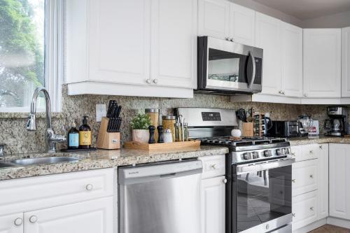 a kitchen with white cabinets and a stove top oven at Charming riverside cottage, walk to beach in Wasaga Beach