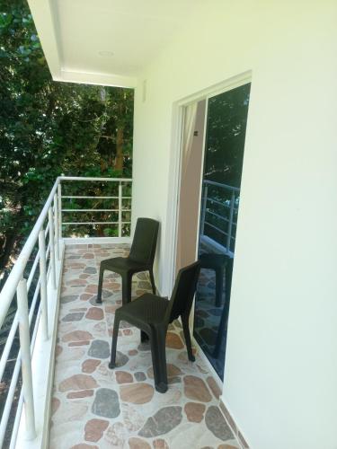a balcony with two chairs and a glass door at Tayrona Fercho's House in Santa Marta