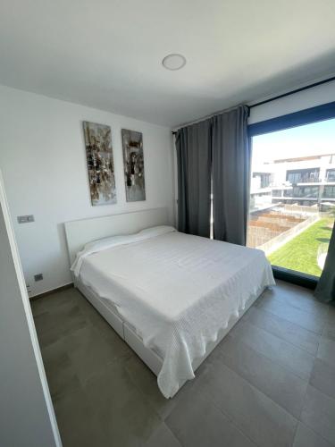 a bedroom with a white bed and a large window at VillaBarrosa Boutique, Ático en Zahara de los Atunes in Zahara de los Atunes