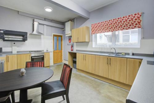 a kitchen with wooden cabinets and a table and a sink at The Sandringham Court Hotel & Apartment Welcoming Large and Small Groups for 15 years in Blackpool