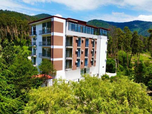 a building on top of a hill with trees at Hotel & Restaurant Emerald Borjomi in Borjomi