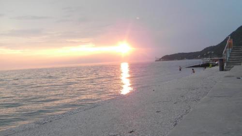 a beach with the sun setting over the water at Affittacamere Alla Stazione in Trieste