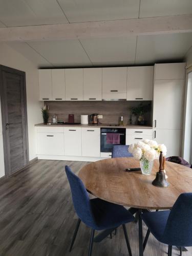 a kitchen with a wooden table and blue chairs at River Apartment in Līči