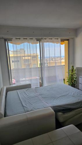 un grand lit dans une chambre avec une grande fenêtre dans l'établissement Studio spacieux lumineux proche plage avec parking privé, à Cagnes-sur-Mer