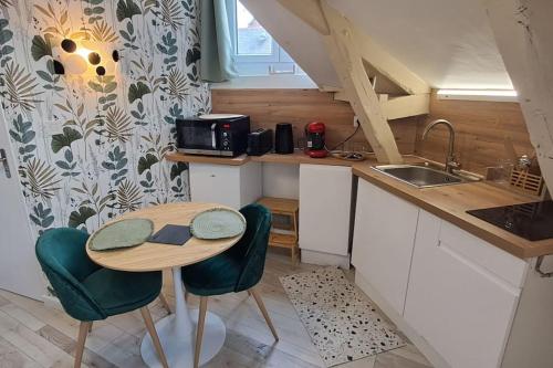 una pequeña cocina con mesa, sillas y fregadero en Studio NOTRE-DAME 3 cœur de ville, en Cholet
