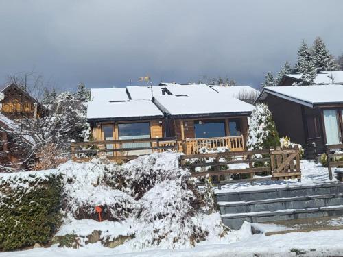 une maison en bois avec de la neige sur le toit dans l'établissement Confortable Chalet pie des pistes Pyrénées 2000, à Bolquère-Pyrénées 2000
