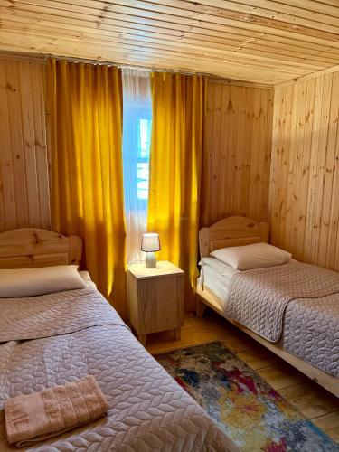 a bedroom with two beds and a window with yellow curtains at Ushguli 12 CENTURY in Ushguli