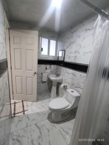 a white bathroom with a toilet and a sink at Hotel Mextlitlán Tierra de Lunas in Zacatlán