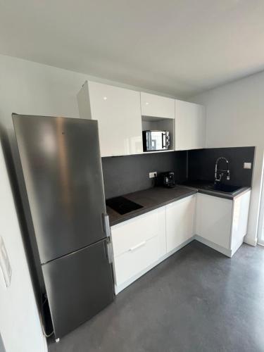 une cuisine avec des armoires blanches et un réfrigérateur en acier inoxydable dans l'établissement Maison contemporaine proche de Lille, à Saint-André