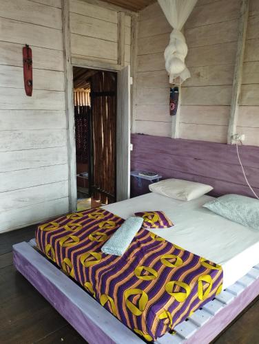 a large bed in a wooden room with a bed sqor at GENTE D'AQUI Ngê D'ai êê in São Tomé