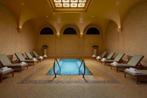 a swimming pool in a large room with chairs around it at The Resort at Pelican Hill in Crystal Cove