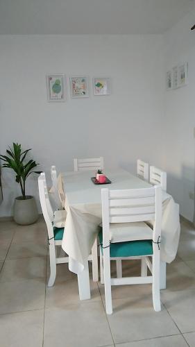 a white table and chairs with a white table and a plant at Casa Fiorella in Ezeiza