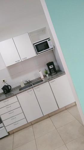 a kitchen with white cabinets and a microwave at Casa Fiorella in Ezeiza