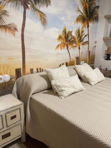 a bedroom with a bed with palm trees in the background at La petite maison de Nadette in Gandía