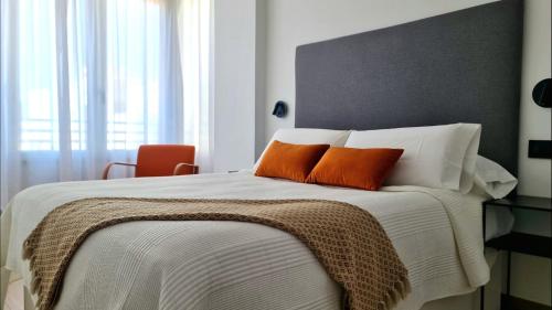 Un dormitorio con una cama grande con dos almohadas naranjas. en Apartment in the center of Alicante, en Alicante