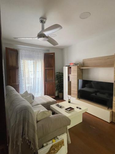 a living room with a couch and a flat screen tv at La petite maison de Nadette in Gandía