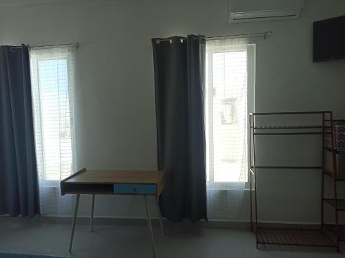 a room with two windows with curtains and a desk at El refugió del colibrí in Mérida