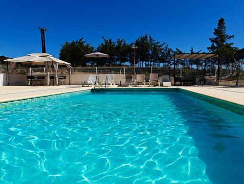 a blue swimming pool with chairs and umbrellas at Quinta da Libelinha Alojamento Local - Mirandela in Mirandela