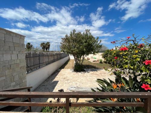 a wooden bench next to a fence and flowers at Veranda sul mare di Donnalucata in Donnalucata