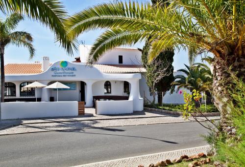 a white house with palm trees and a street at Sao Rafael Holidays in Albufeira