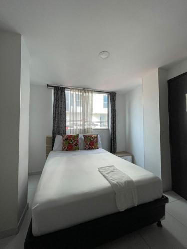 a bedroom with a large white bed with a window at Hotel Guadalupe Plaza in Pereira