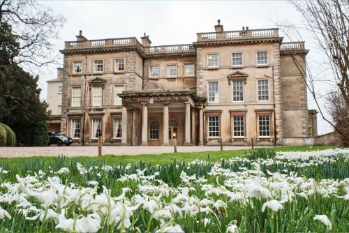 an old mansion with a field of white flowers at Cosy & Chic in great location near Loughborough Uni & East Midlands Airport in Loughborough