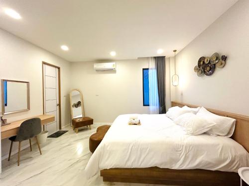 a bedroom with a large white bed and a desk at nanapoolvilla ruamchok in Chiang Mai