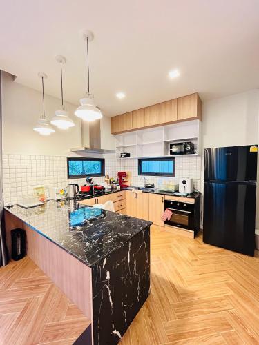 a large kitchen with a black refrigerator and wooden floors at nanapoolvilla ruamchok in Chiang Mai