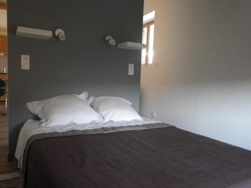 Un dormitorio con una cama con almohadas blancas y una ventana en Ténorilo, en Saint-Victor-sur-Loire