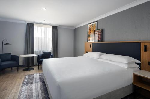 a bedroom with a large white bed and a desk at Edinburgh Marriott Hotel Holyrood in Edinburgh