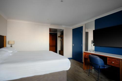 a hotel room with a bed and a desk with a tv at Edinburgh Marriott Hotel Holyrood in Edinburgh
