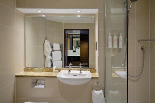 a bathroom with a sink and a shower with a mirror at Edinburgh Marriott Hotel Holyrood in Edinburgh