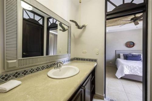 a bathroom with a sink and a mirror and a bed at Jaco Beachfront Oasis Newly renovated dream condo in Jacó