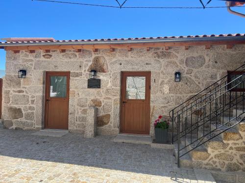 a stone house with two doors and a staircase at Eido de Bairros - Casa Cantinho da Touça in Soajo