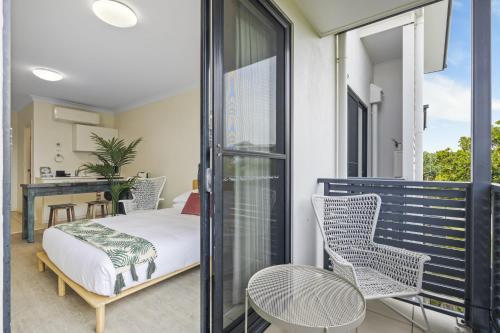 a room with a bed and chairs on a balcony at Comfy Studio Apartment in Marcoola Beach in Marcoola