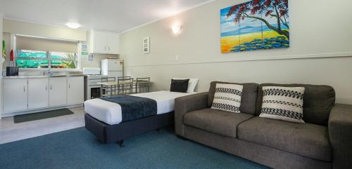 a room with a bed and a couch and a kitchen at Hihi Beach Holiday Park in Mangonui