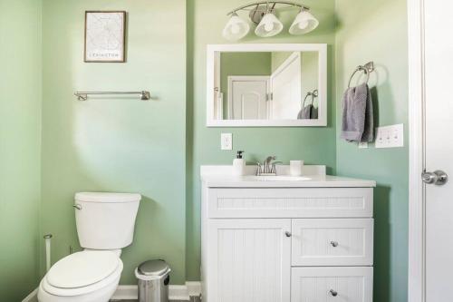 a bathroom with a toilet and a sink and a mirror at El Retro- Mid Century Ranch near Horse Park & Rupp in Lexington
