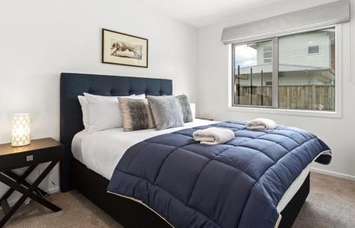 Schlafzimmer mit einem großen blauen Bett und einem Fenster in der Unterkunft Tranquil @ Taupo in Taupo