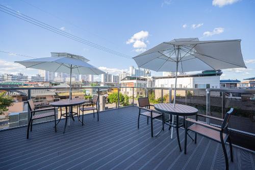 two tables and chairs on a balcony with umbrellas at Brown Dot Hotel Sangju in Sangju