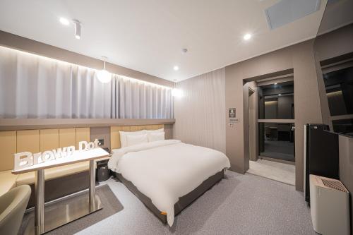 a bedroom with a white bed and a television at Brown Dot Hotel Sangju in Sangju