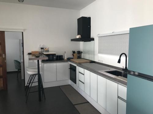 a kitchen with white cabinets and a sink and a stool at Villa Beau Rivage in Bachok