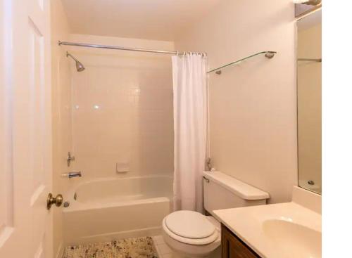 a bathroom with a toilet and a tub and a sink at 3 Bedroom Townhouse 8 Miles to Washington DC in Falls Church