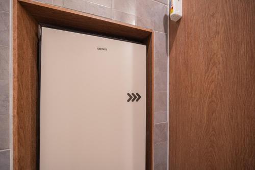 a white door in a bathroom with a tile wall at Brown Dot Hotel Sangju in Sangju