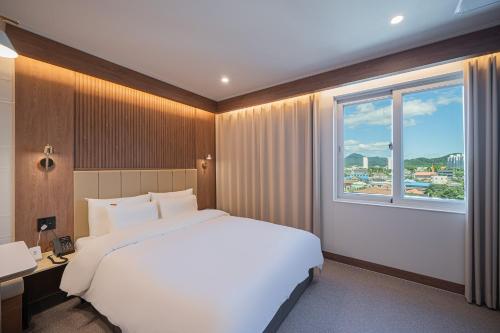 a bedroom with a large white bed and a window at Brown Dot Hotel Sangju in Sangju
